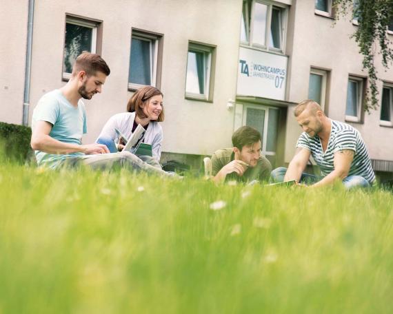 Gruppe Studenten auf Wiese vor Wohnanlage
