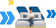Junge Frau sitzt mit Laptop auf einem Bett