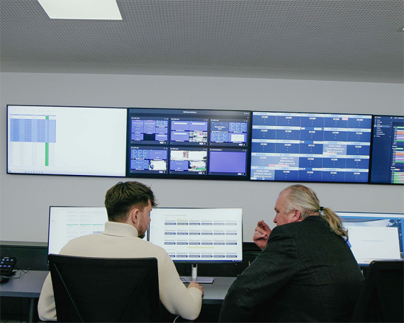 Zwei Mitarbeiter und viele Monitore