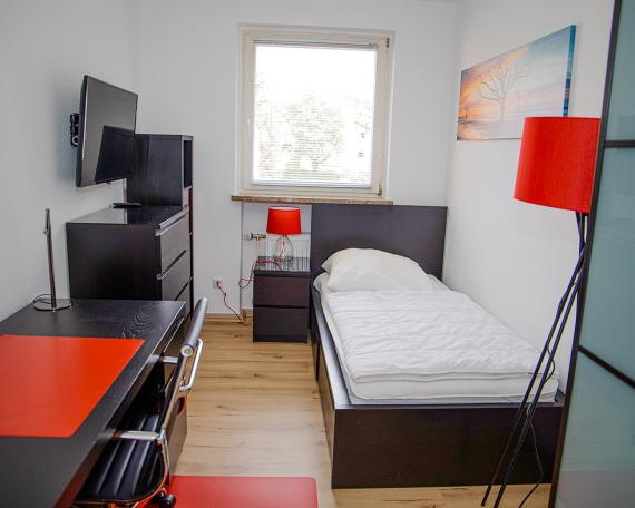 Zimmer mit Bett, Schreibtisch und Kommode